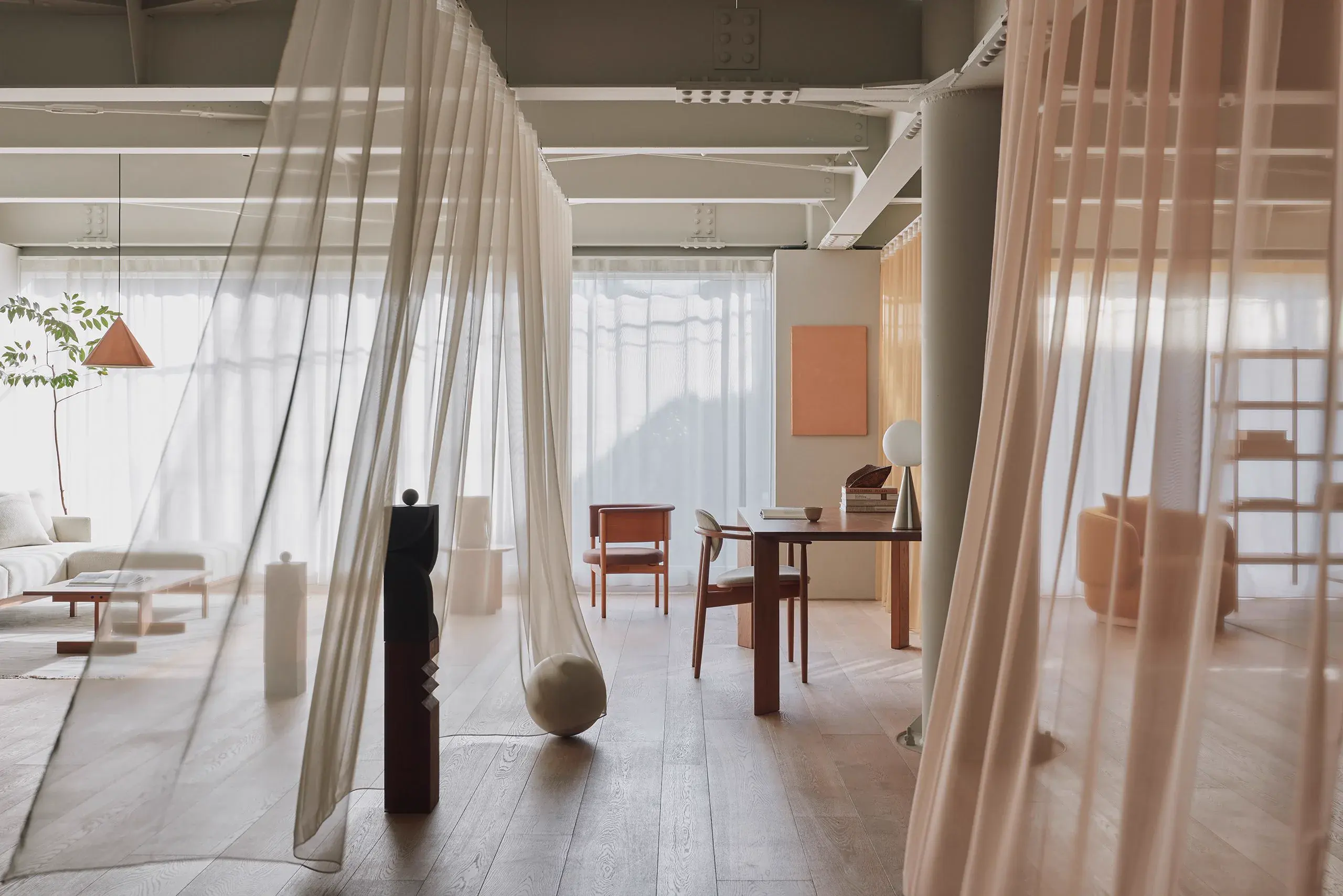 Sheer draped curtains dividing a warm, minimal interior