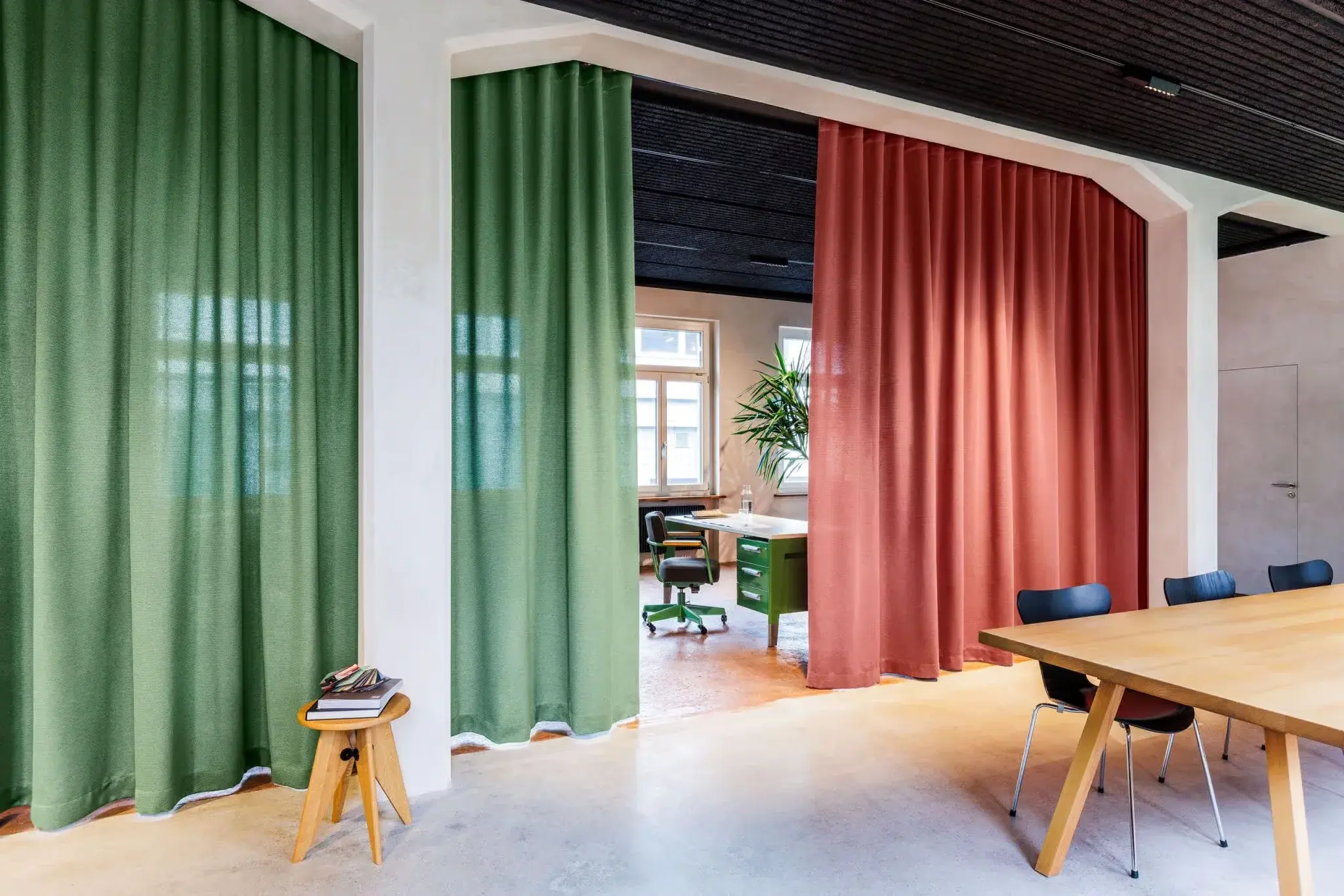 Green and terracotta curtains partitioning a meeting room and workspace